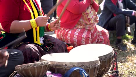 close up of a woman's hand playing an old drum like nepali instrument during the celebration