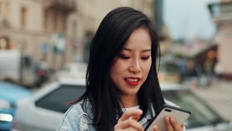 Primer-Plano-De-La-Joven-Hermosa-Mujer-Tocando,-Escribiendo-Y-Enviando-Un-Mensaje-De-Texto-En-El-Teléfono-Inteligente-Mientras-Está-De-Pie-Fuera-De-La-Ciudad