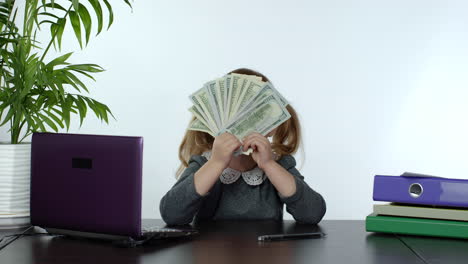 Child-girl-boss-earns-money.-Little-boss-kid-hold-much-dollars-cash-in-her-hands-in-the-office