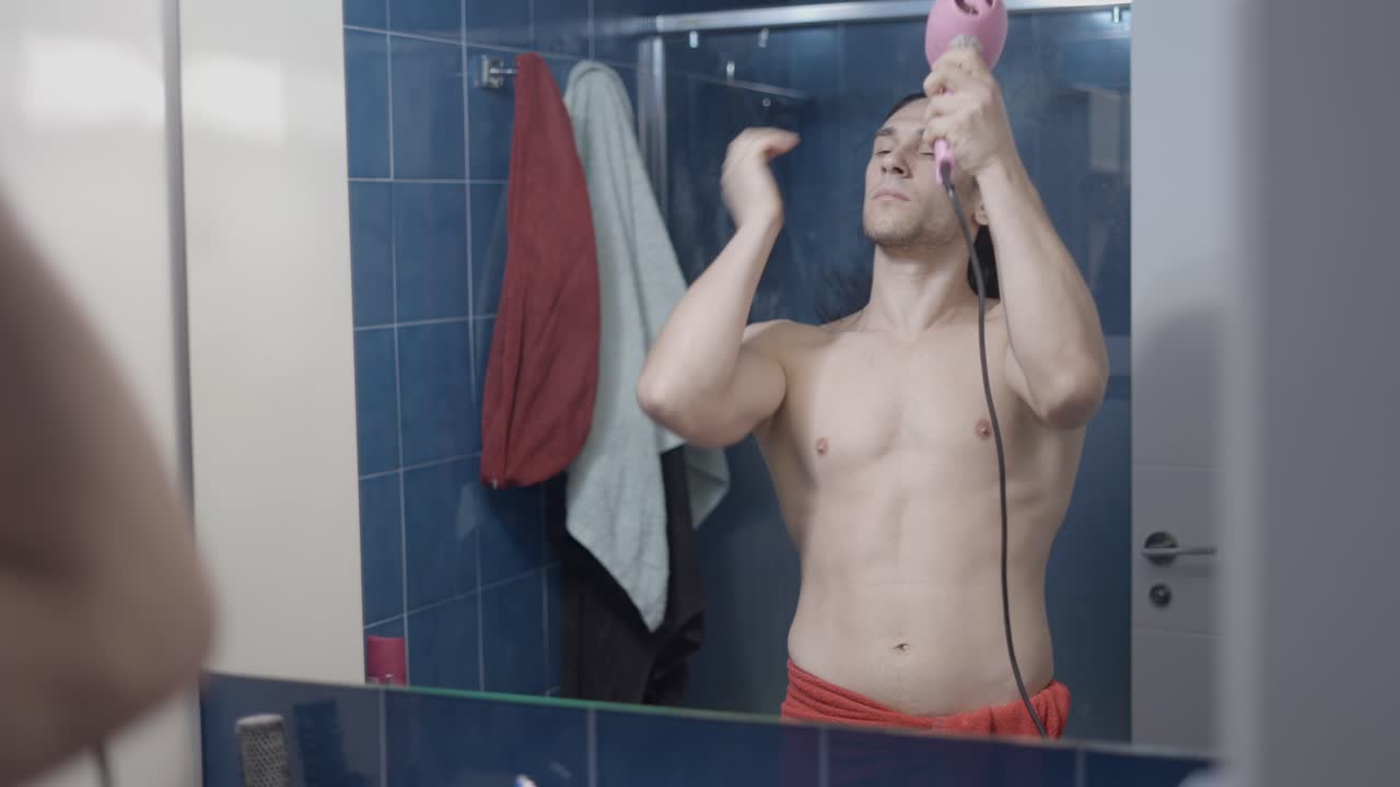 Man drying his hair in a bathroom