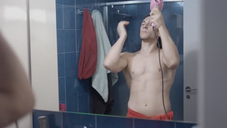 man drying his hair in a bathroom