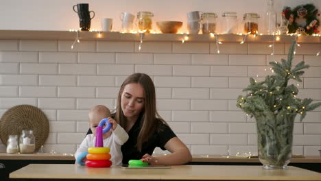 niño pequeño con mamá jugando con el juguete en la habitación de la guardería. mamá con su bebé de 1 año divirtiéndose en casa