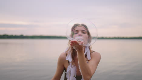 una joven artista muestra trucos de magia usando burbujas de jabón. cree burbujas de jabón en sus manos e inflelas ubicación espectáculo de circo teatral al atardecer