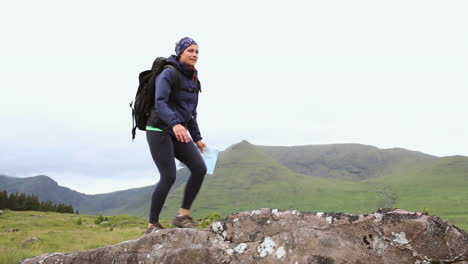 hiking woman reaching the summit and looking around with a map