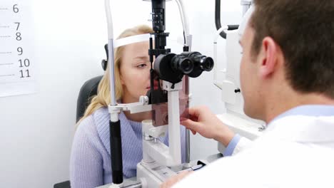 optometrist examining female patient on slit lamp