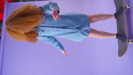 Vertical-Video-Of-Young-Girl--Standing-Riding-On-Skateboard-Against-Purple-Background