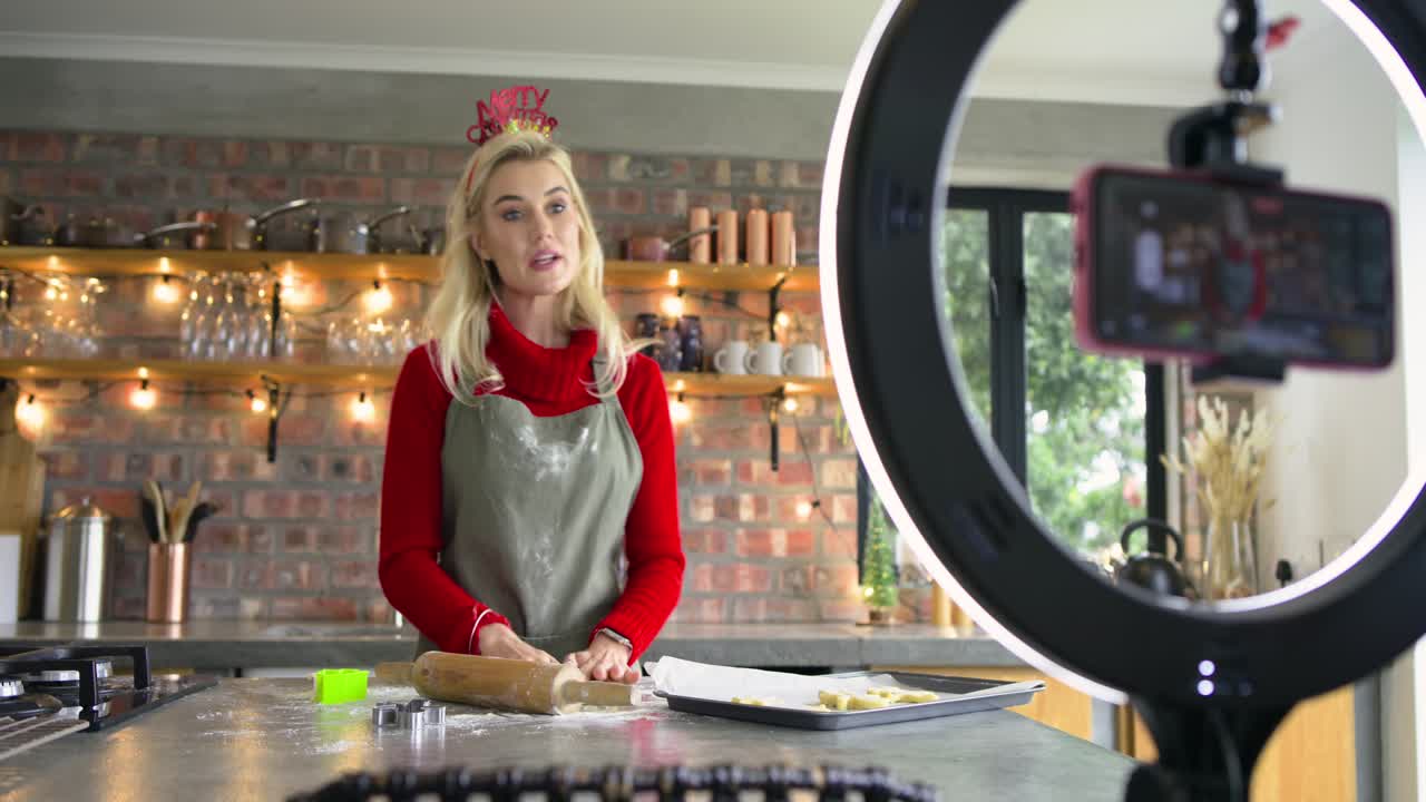 Woman wearing green apron rolling dough in kitchen stamping cookies using cutter showing technique