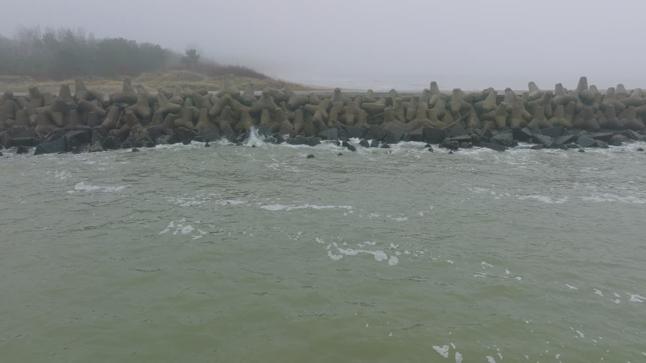 리파야 콘크리트 부두 항구, 발트해 해안선, 짙은 안개가 낀 안개 낀 날, 변덕스러운 느낌, 큰 폭풍우가 튀는 것, 넓은 드론 돌리 샷이 바로 낮게 움직이는 모습