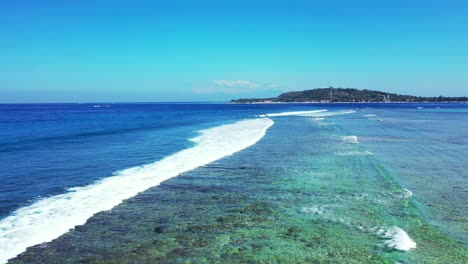aerial of shallow waves breaking on a beautiful coral reef off the coast of a beautiful beach island