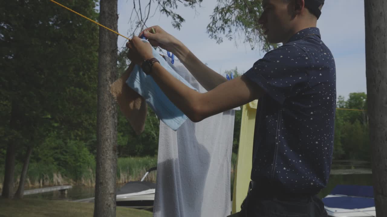 Man Getting The Face And Bath Towels Hanging On The Clothesline For Drying Under The Sun - close up slowmo