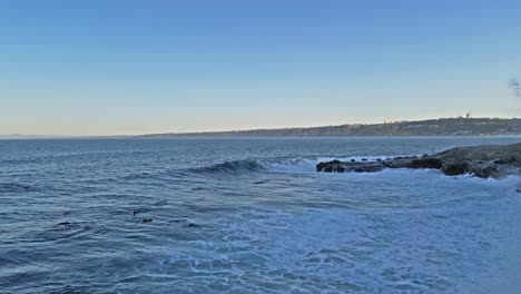 Tiro-De-Dron-De-Leones-Marinos-Jugando-Y-Saltando-En-El-Surf-En-La-Jolla,-California-Con-Horizonte-A-La-Vista-Durante-La-Marea-Real