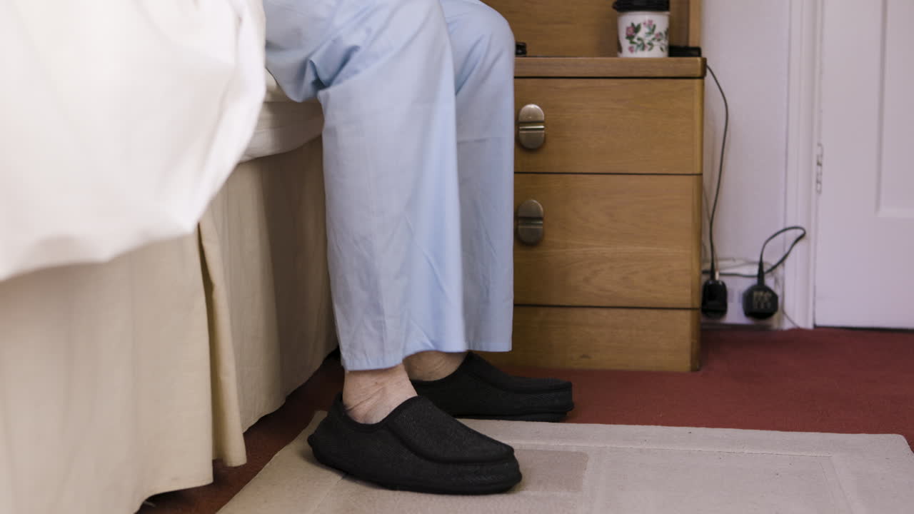 A person wearing slippers and pajamas in a bedroom