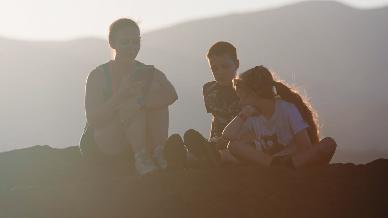 Family Sitting on a Hilltop at Sunset or Sunrise