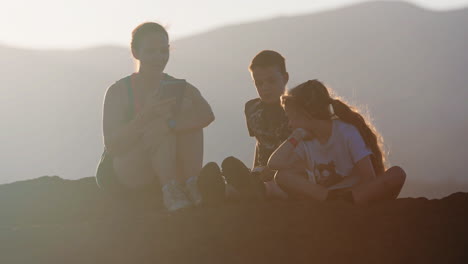 family sitting on a hilltop at sunset or sunrise