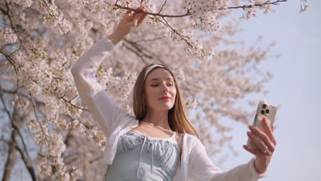 young carefree woman taking selfie on blooming sakura flowers at seocho, seoul city, south korea