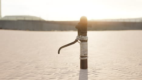 Rusty-old-metal-water-pump-on-sand-beach