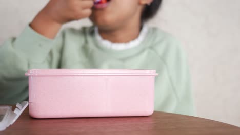 child eating a strawberry from lunchbox
