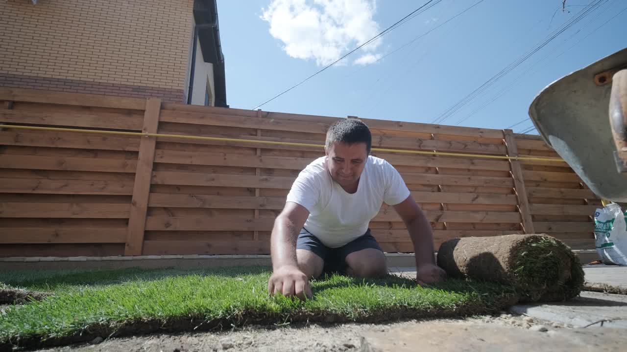 잔디 설치 및 조경 프로젝트를 위해 뒷마당 정원에 소드 풀을 는 사람, 주거 마당의 신선하고 푸른 잔디를 위해 집 개선 및 야외 유지에 초점을 맞추고 있습니다.