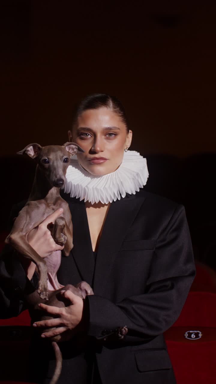 Woman holding a dog in a historical inspired outfit.