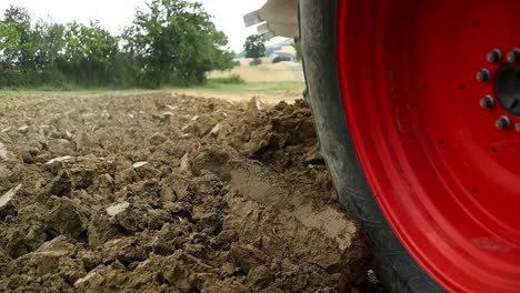 a plowing soil tractor driving by plowing up dirt from the ground on a farm, static close up