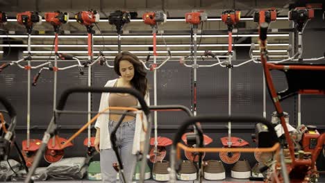 a young woman examines lawn mowers for her garden. shopping for gardening.