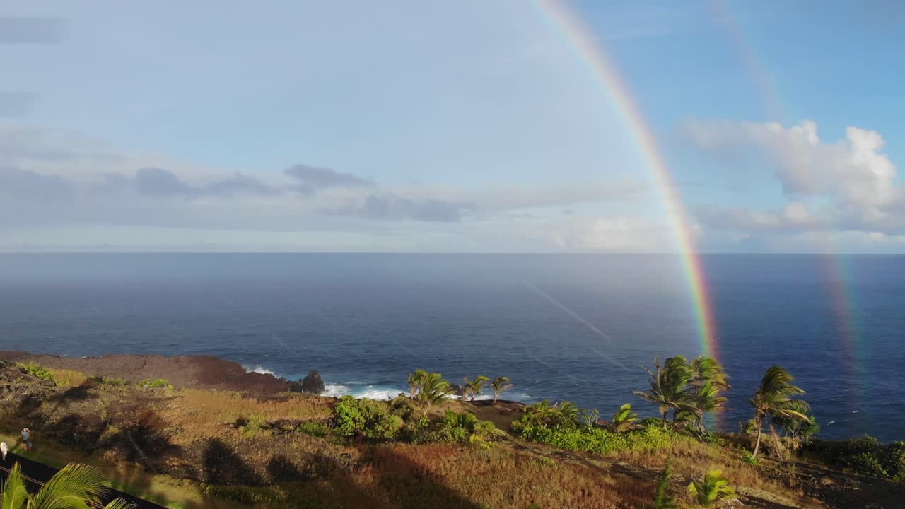 dos o doble arco iris sobre el océano pacífico con acantilados en primer plano al atardecer