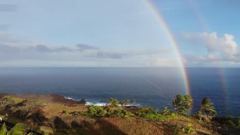 two or double rainbow over the pacific ocean with cliffs in the foreground at sunset