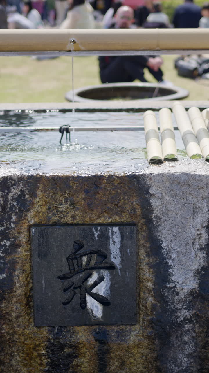 Close up of a purification fountain in the cour of the Tsukiji Hongan-ji Temple in Chuo, Japan. Vertical. Translation: "Ritual water"