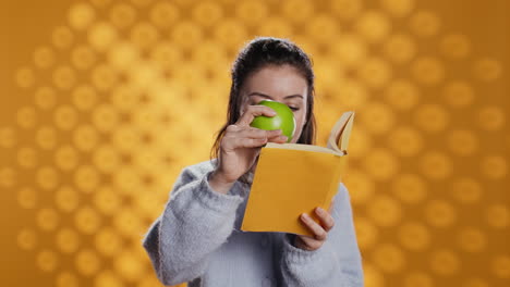 Mujer-Leyendo-Un-Libro-Y-Disfrutando-De-Manzana-Fresca,-Viviendo-Sanamente,-Fondo-De-Estudio