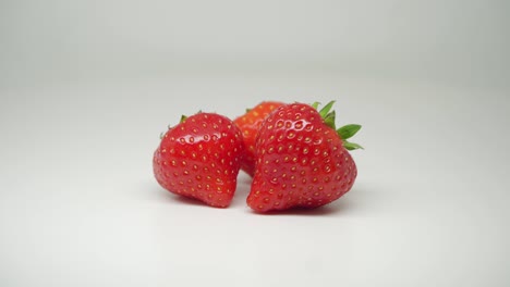 Three-Delicious-Red-Strawberries-At-The-Top-Of-The-Table---Close-Up-Shot