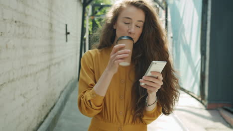 woman drinking coffee and using phone in urban setting