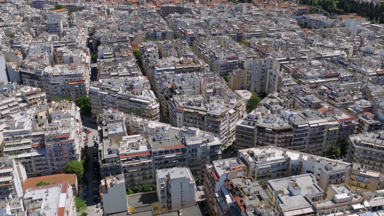 Vista aerea degli isolati urbani densamente popolati di Salonicco, che mostra un mix di tetti, cortili e strade strette.