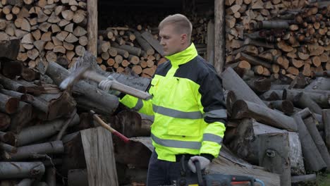 Lumberjack-worker.-Man-woodcutter-holds-big-axe-and-electric-chainsaw-on-his-hands.-Firewood