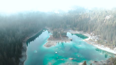 drone volando a través de las nubes para revelar un prístino lago de agua azul caumasee con bosques alrededor en suiza