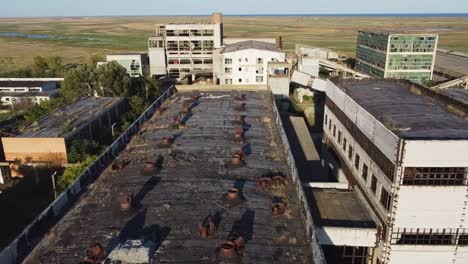 Approaching-drone-and-slightly-pivoting-to-the-left-side-of-the-frame,-above-a-run-down-building-of-a-former-rare-metals-enterprise,-located-in-Vadu,-Romania