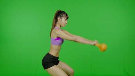 mujer en forma levantando kettlebell en pantalla verde, hacia adelante, ambas manos, vista lateral, clave de croma, tecnología, realidad aumentada. mujer asiática, para superposición gráfica y propósitos de corte.