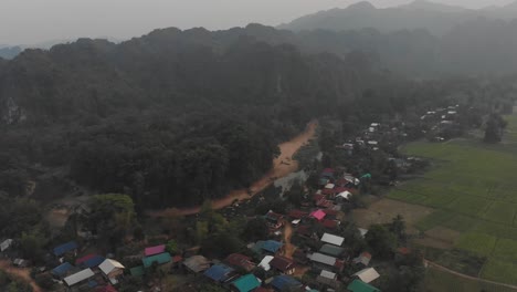 Vista-Por-Drones-De-Un-Pequeño-Pueblo-Rural-Cerca-De-La-Cueva-De-Kong-Lor-En-Un-Día-Nublado,-Aéreo