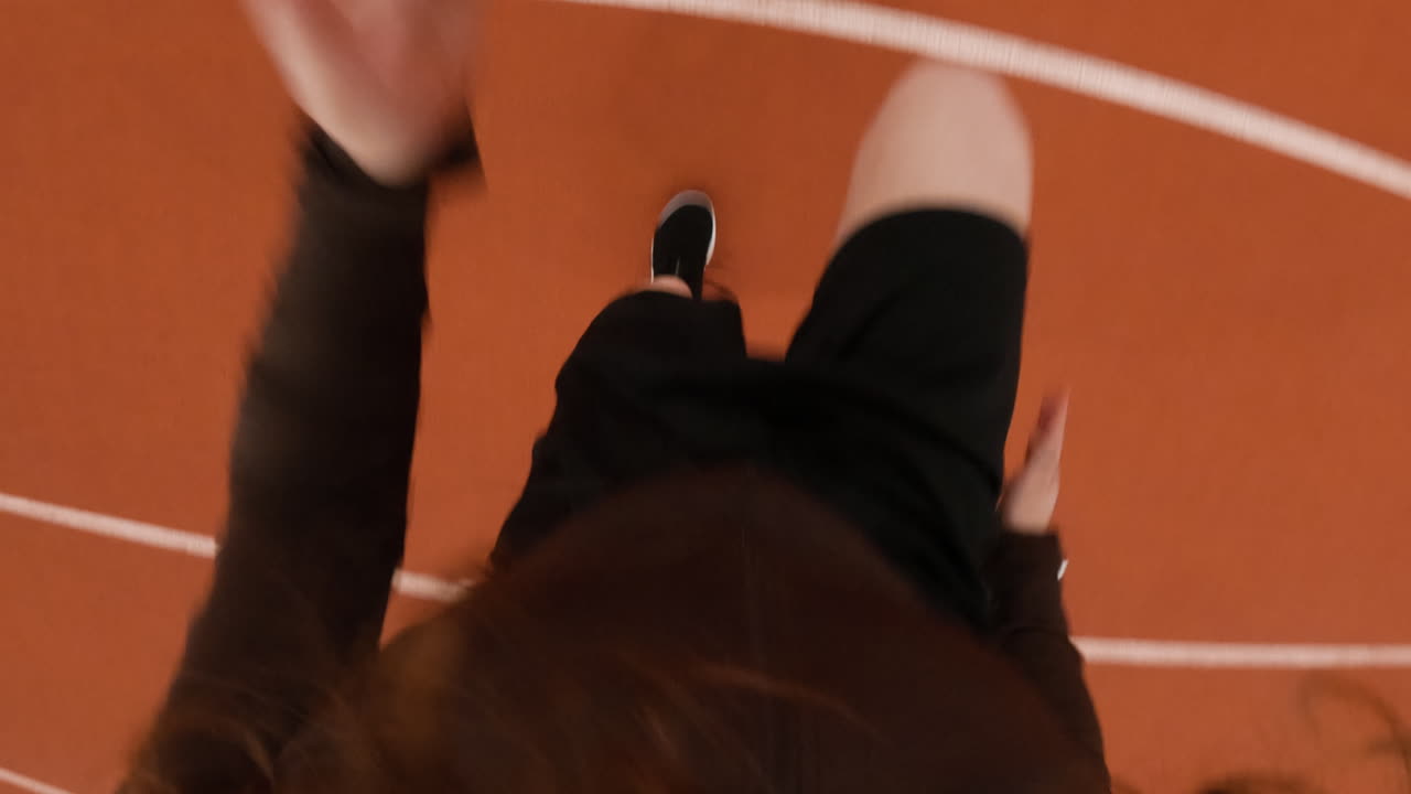 First-person perspective of a person running on an indoor track