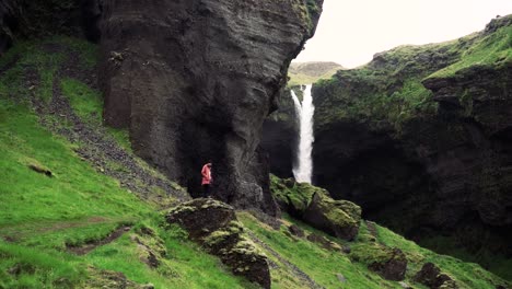 tomas en cámara lenta de una remota cascada islandesa con un hombre caminando hacia ella