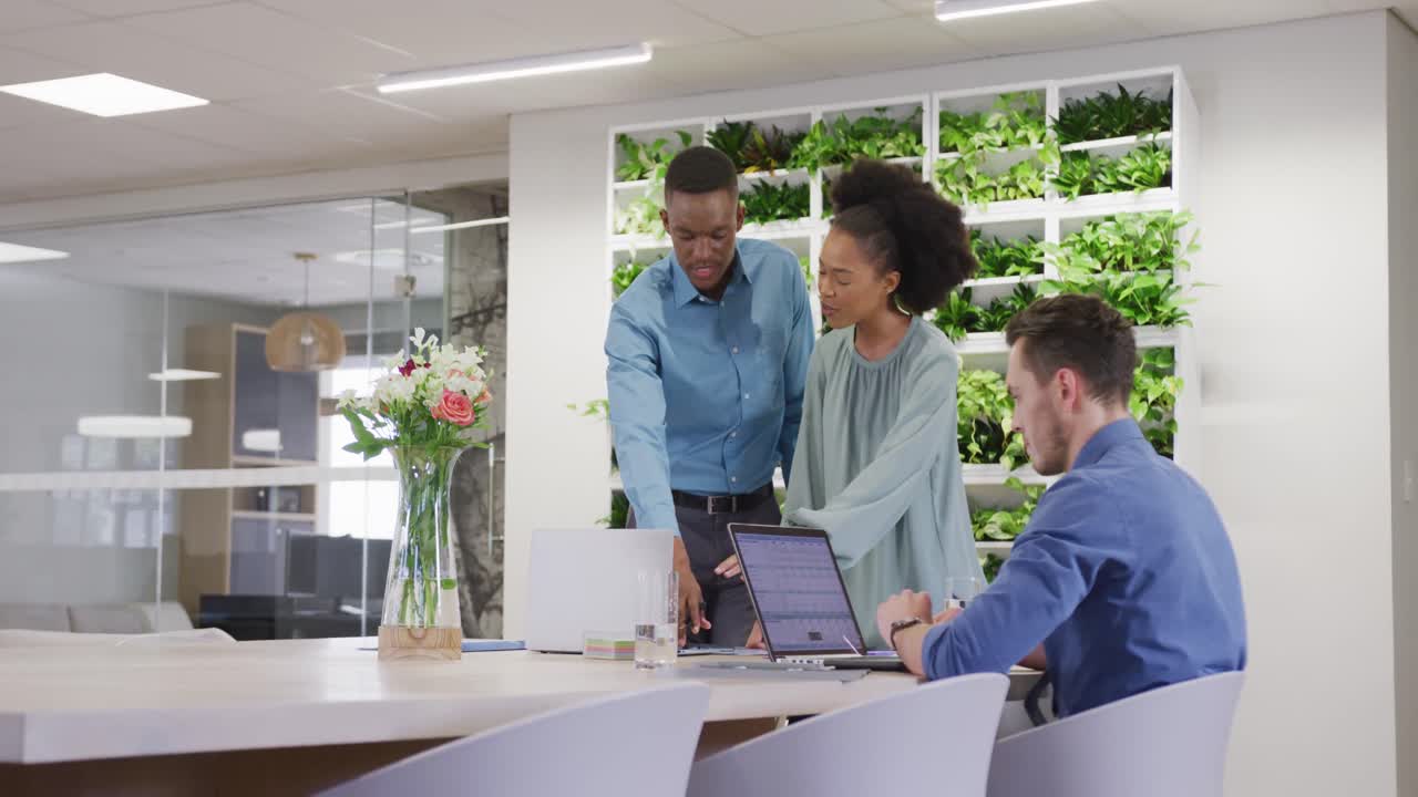 Happy diverse business people discussing work and using laptop at office, slow motion
