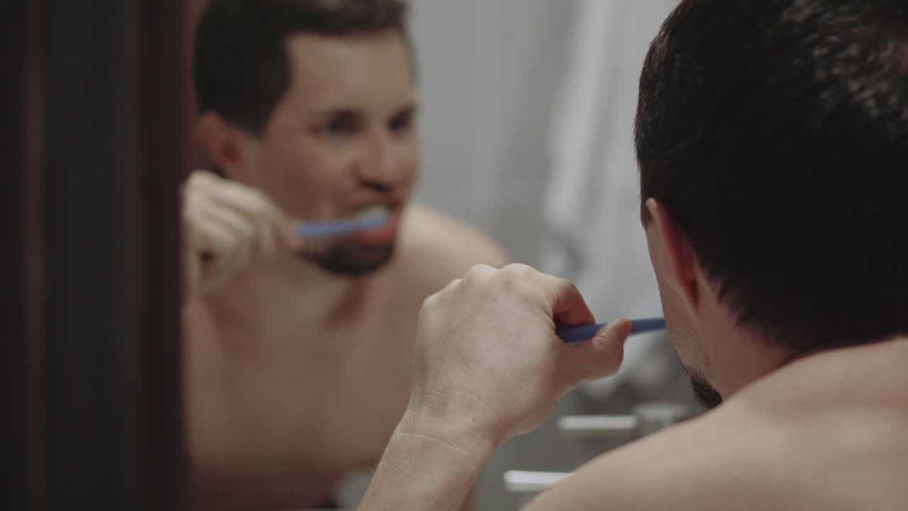 Homem a escovar os dentes na casa de banho