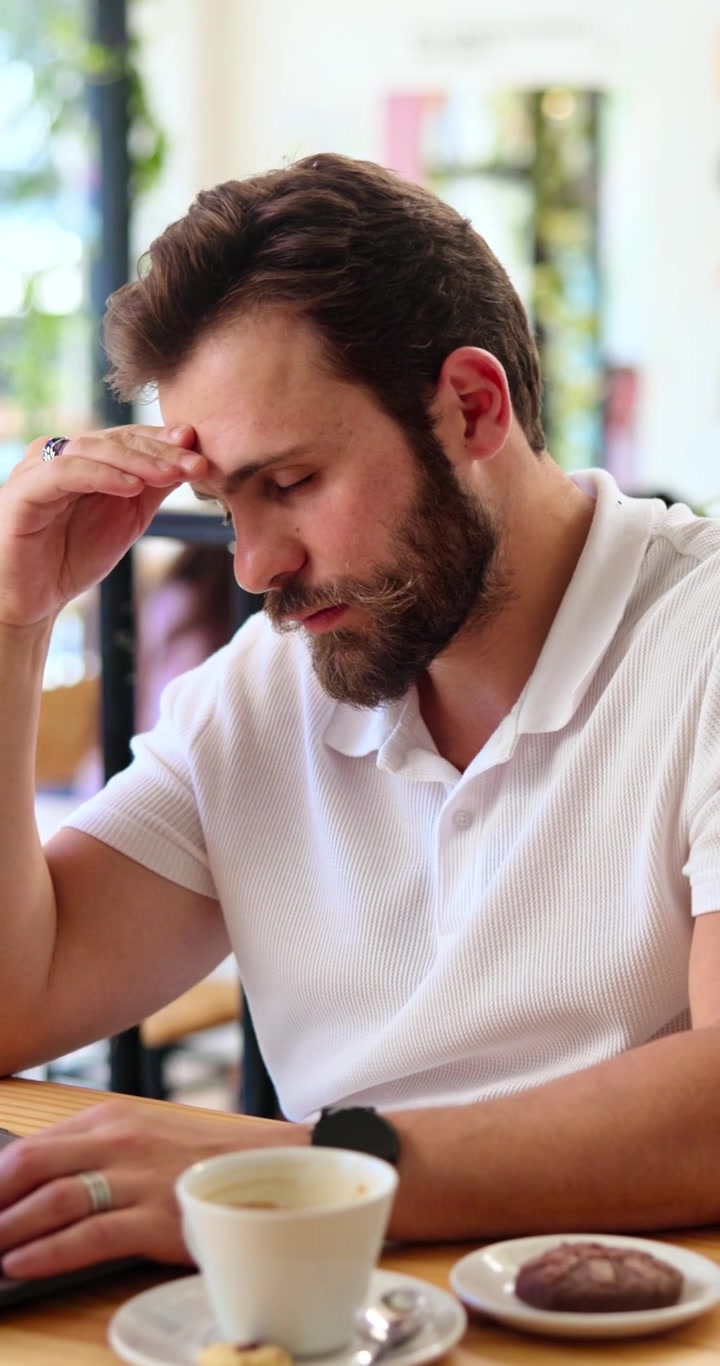 Uomo stressato che lavora al portatile in un bar