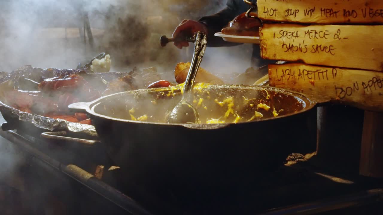 comida vaporizada sendo preparada em uma panela grande em uma barraca de comida movimentada no mercado de natal à noite