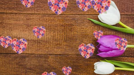 Animation-Von-Herzen-Aus-Bunten-Blumen,-Die-über-Einer-Holzoberfläche-Schweben,-Mit-Weißen-Und-Rosa-Tulpen