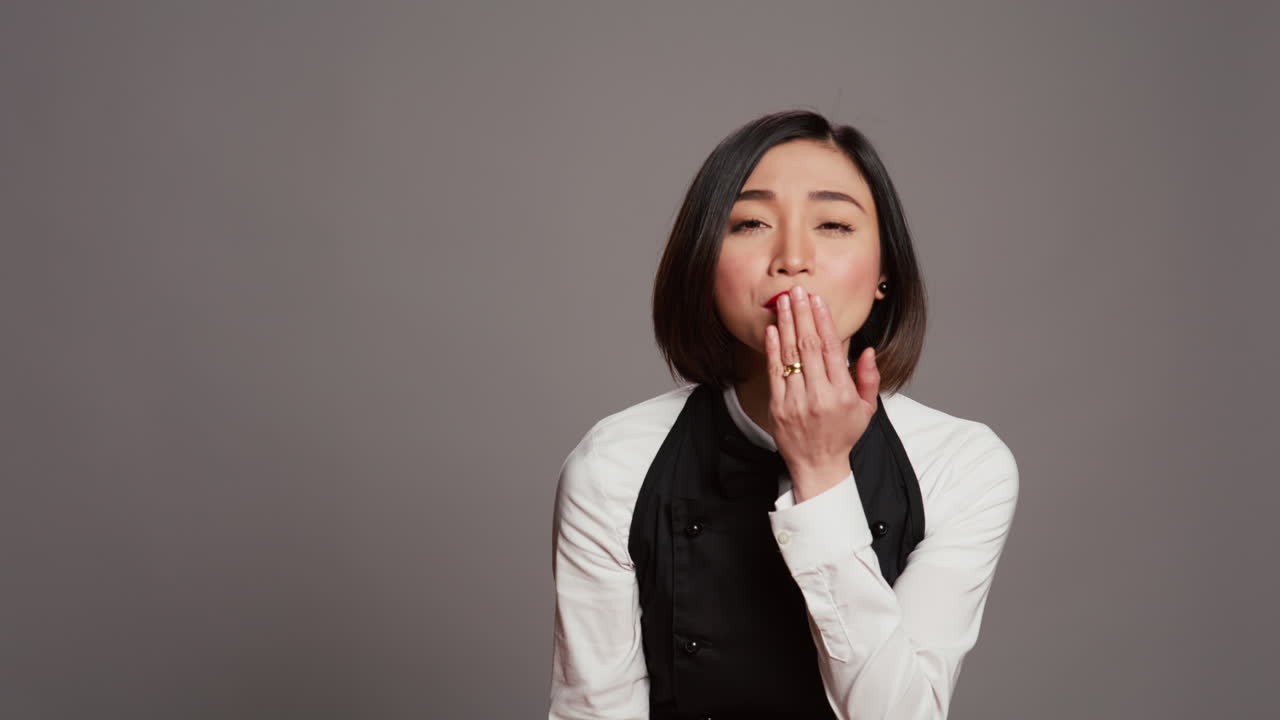 귀여운 유혹적인 웨이트리스가 카메라 앞에서 공기 키스를 불어넣습니다.