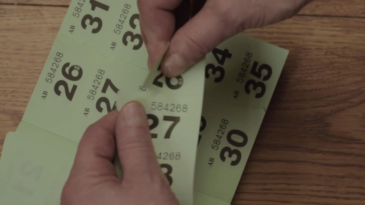 Hand tearing and folding lottery tickets overhead close up shot