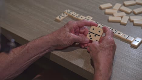 senior citizen is forced to think about his next move during a game of dominoes