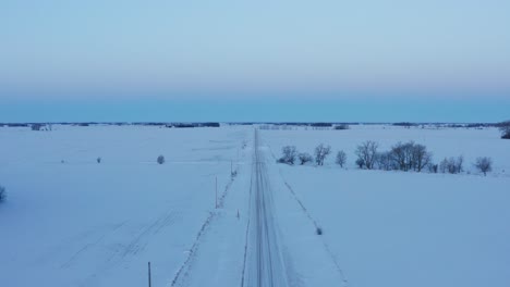 aerial, snow covered straight road in rural countryside, vast snow field, pastel colors