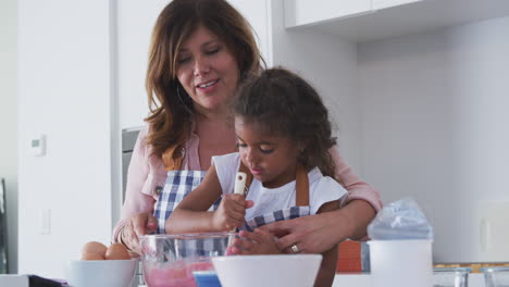 abuela y nieta hispanas divirtiéndose en la cocina haciendo pastel juntas