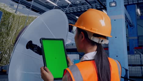 ingeniero inspeccionando antena parabólica con tableta en la fábrica